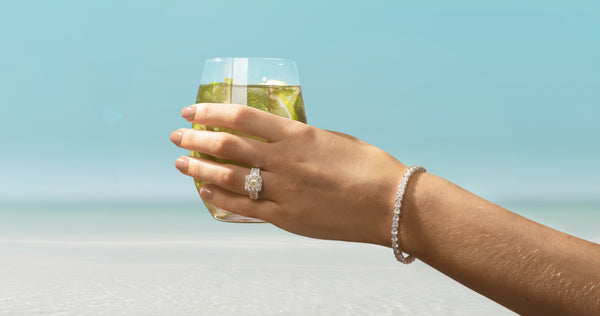 Model wearing diamond ring and bracelet holding a drink