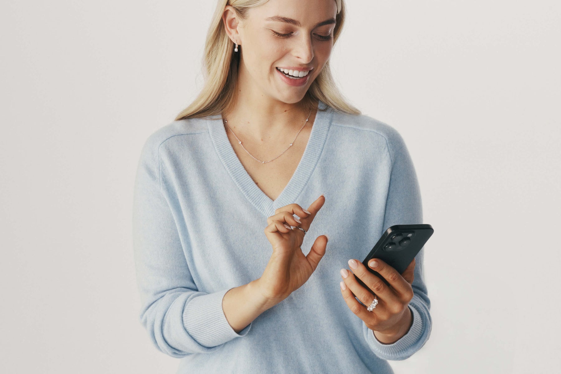 Model wearing natural diamond jewellery and holding a phone online shopping